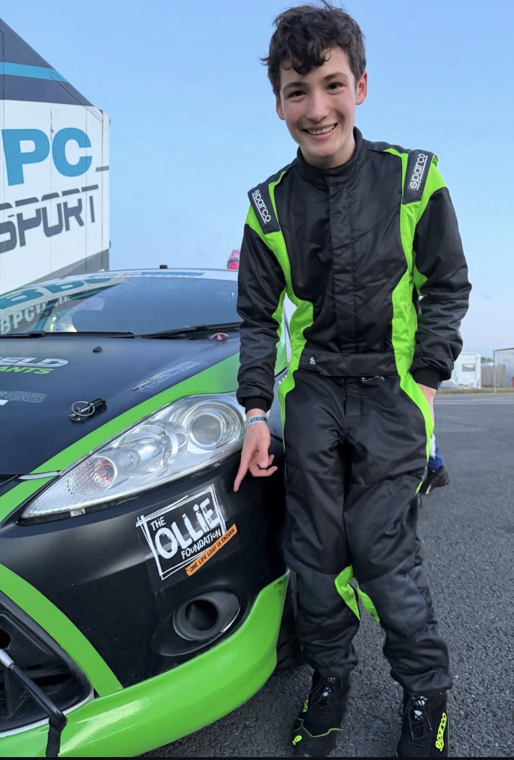 Thomas Potter in his Sparco racing suit beside his car at the circuit