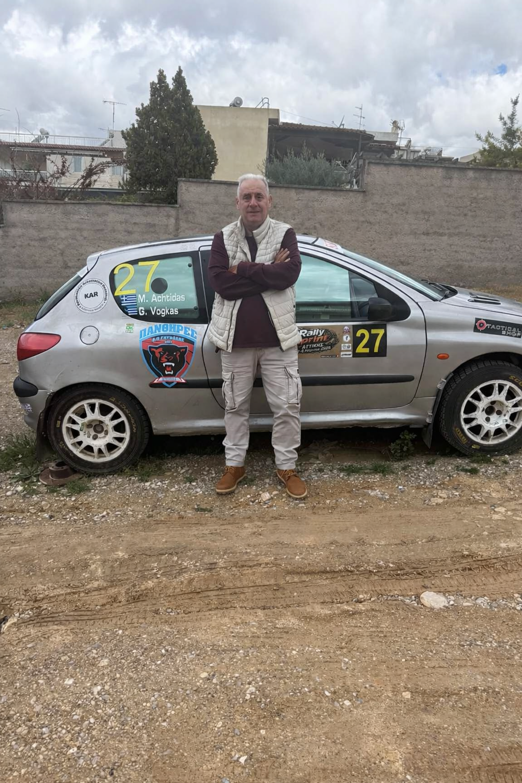 Manos Achtidas beside his Peugeot 206 rally car, number 27, at a Greek rally event